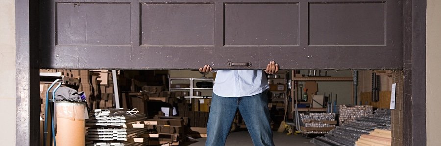 man opening broken garage door by hand