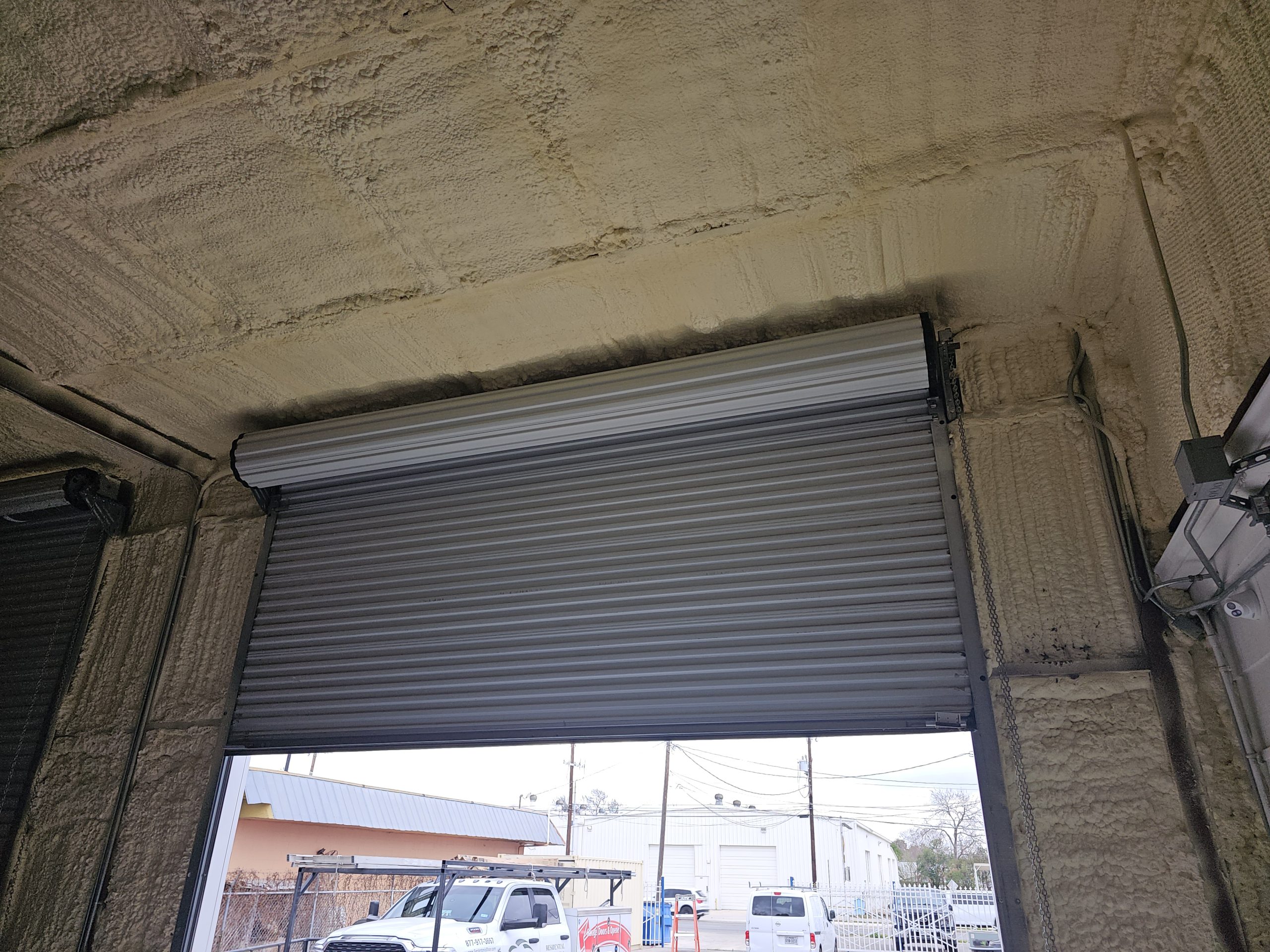 What do I need to know about installing a roll-up garage door in a building with spray foam insulation?